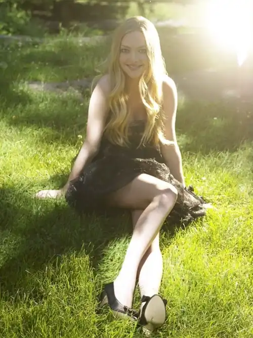 Amanda sitting on the grass wearing a short dress